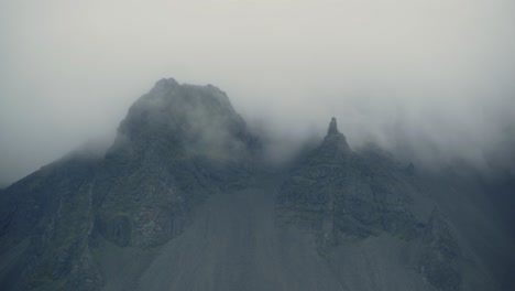 clouds roll through jagged mountain peaks in iceland on a stormy day