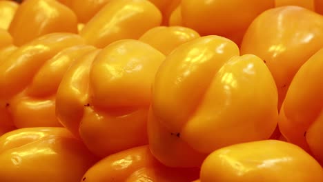 a hand picks a yellow bell pepper from a vibrant display under warm lighting in a supermarket