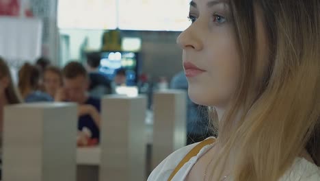 young beautiful girl looks around standing in a cafe