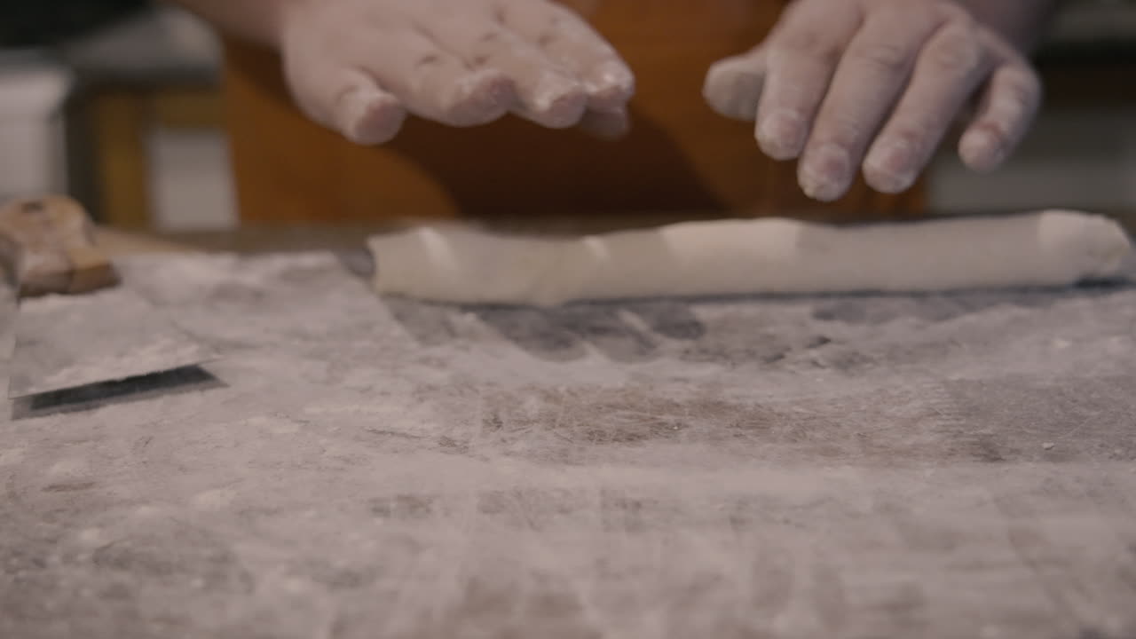 Primo Piano di Mani Che Stendono l'Impasto su una Superficie Infarinata