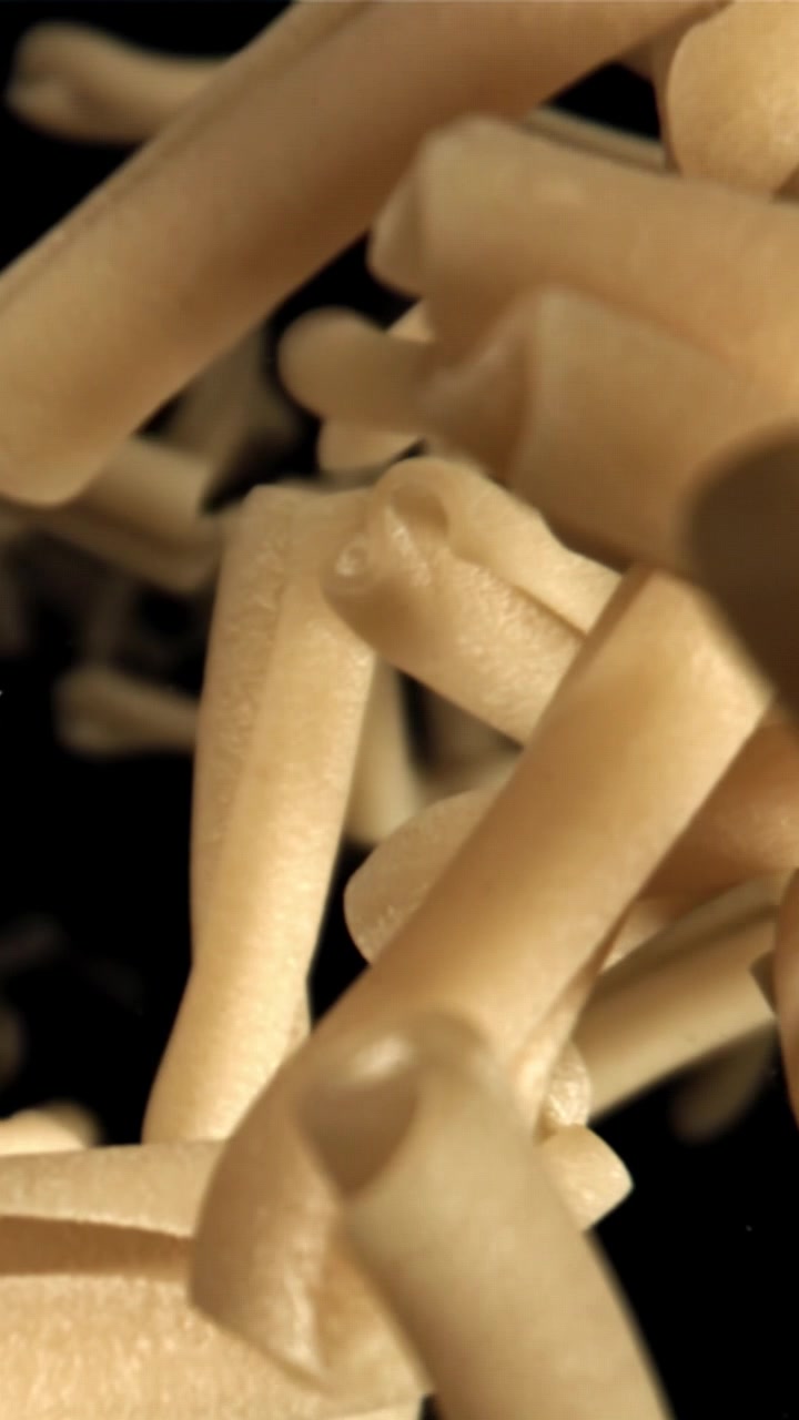 Primo piano di pasta cruda che cade al rallentatore su sfondo nero