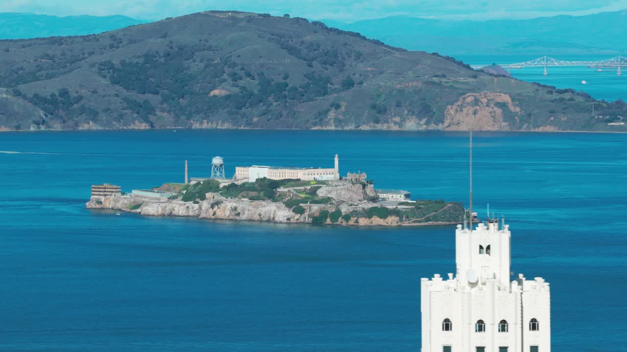San Francisco, California’da mükemmel bir günde gökdelenlerle çerçevelenmiş Alcatraz Adası’nın telefoto dolly havadan çekimi. 4K