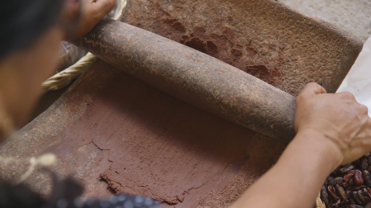 moler granos de cacao usando métodos tradicionales para hacer chocolate