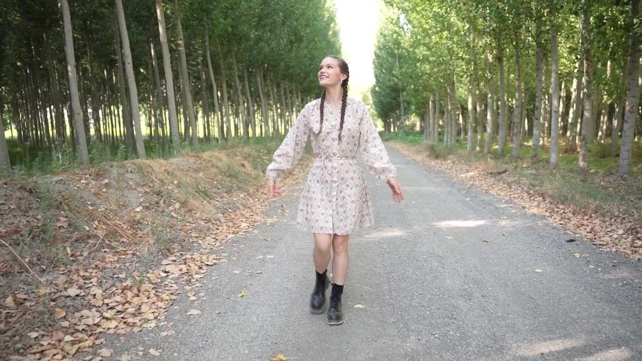 Una giovane ragazza cammina gioiosamente lungo un bellissimo sentiero alberato in una luminosa giornata di sole.