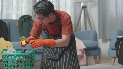 ama de llaves masculina asiática con un delantal limpiando la habitación desordenada de los juguetes