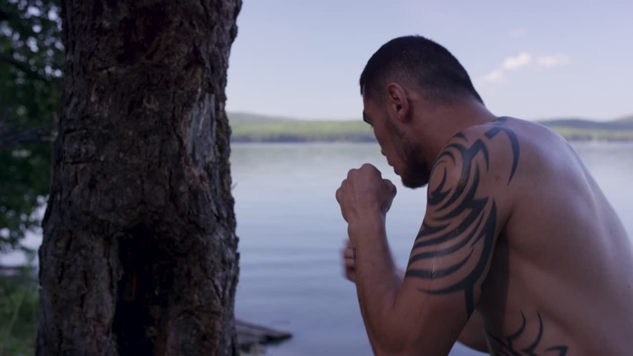 hombre practicando ejercicios de boxeo al aire libre junto a un lago