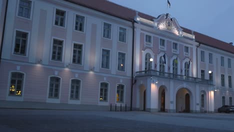 video shows estonian parliament building or government building that is slightly pink colored lighted with lights during evening or dusk on the walls