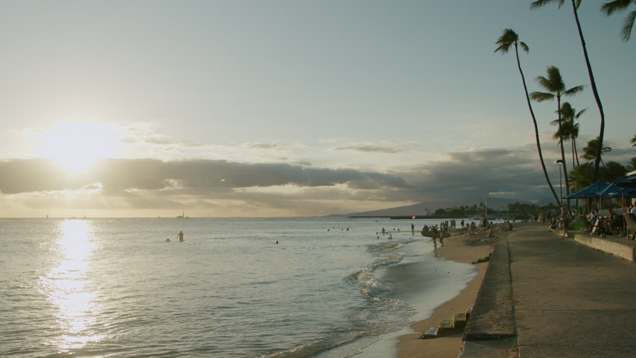 Atardecer en una playa tropical con personas y palmeras