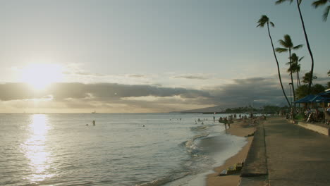 sunset on a tropical beach with people and palm trees