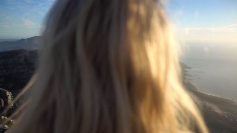 slowmotion over the shoulder on top of table mountain in capetown during sunset with a young blond woman