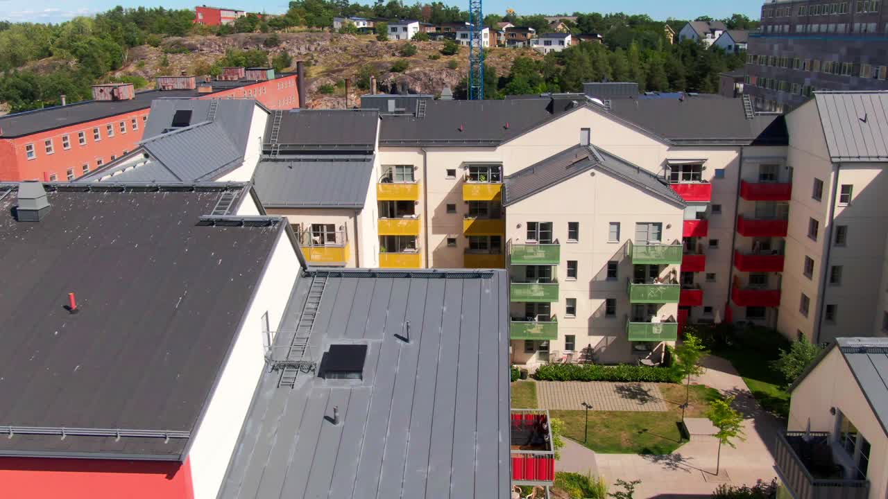 Dinamiche riprese aeree di moderni appartamenti con balconi vivaci gialli e rossi, piante verdi e cortili in Svezia
