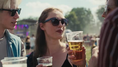 group of friends spending time together at music festival and drinking beer.