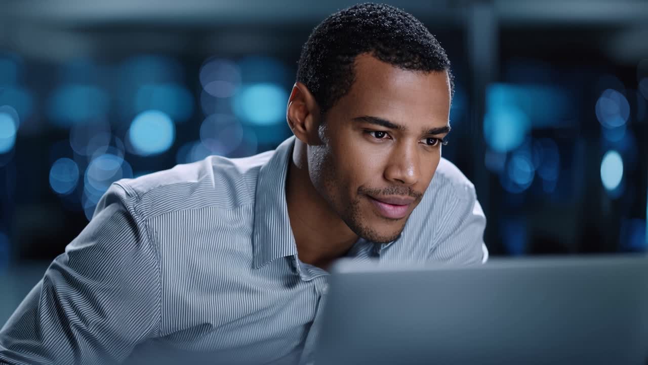 Focused Professional Analyzing Data on Laptop with Bluish Background in a Modern Office Environment for Enhanced Productivity and Insightful Decision-Making