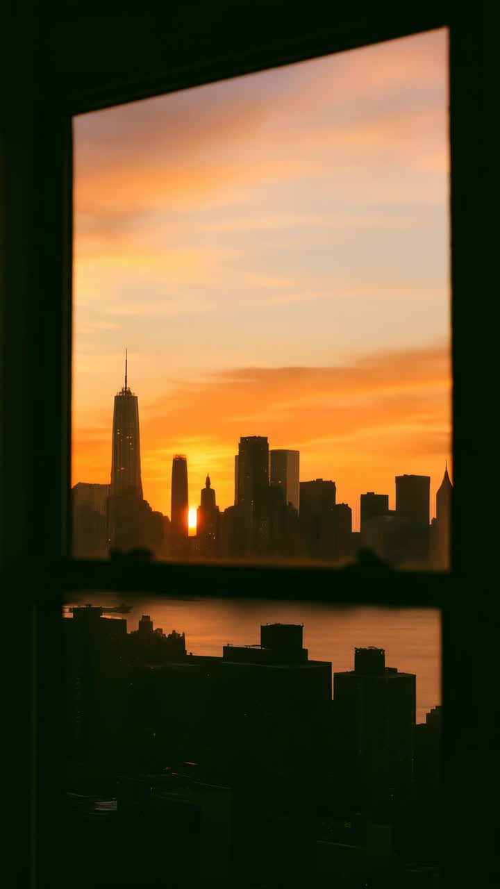 Un video captura el horizonte de una ciudad al atardecer a través de una ventana, con un brillo cálido y un ángulo picado