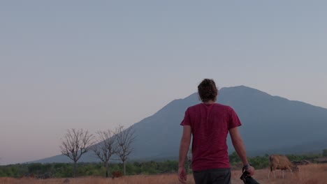 A-man-walks-through-Savanna-Tianyar-in-Bali-with-a-camera-at-sunrise