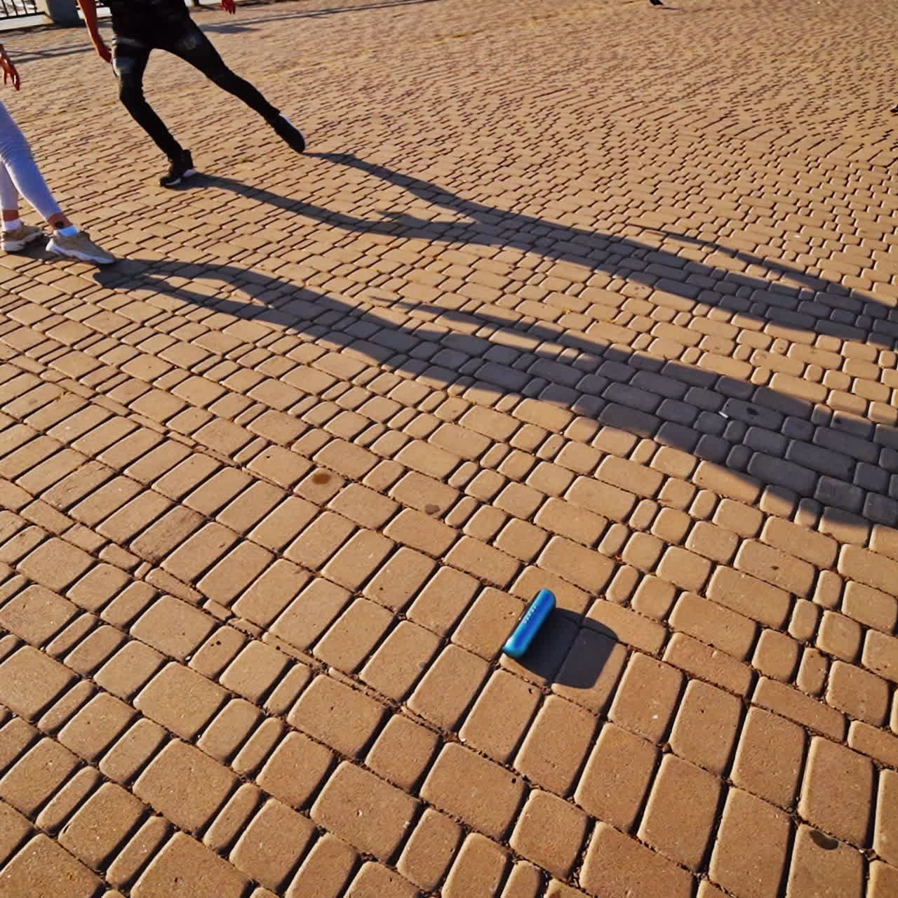 Modern dancers are dancing in the street. Urban lifestyle. Hip-hop generation. Boy's and girl's legs on the video. Paving stones and shades at sunset.
