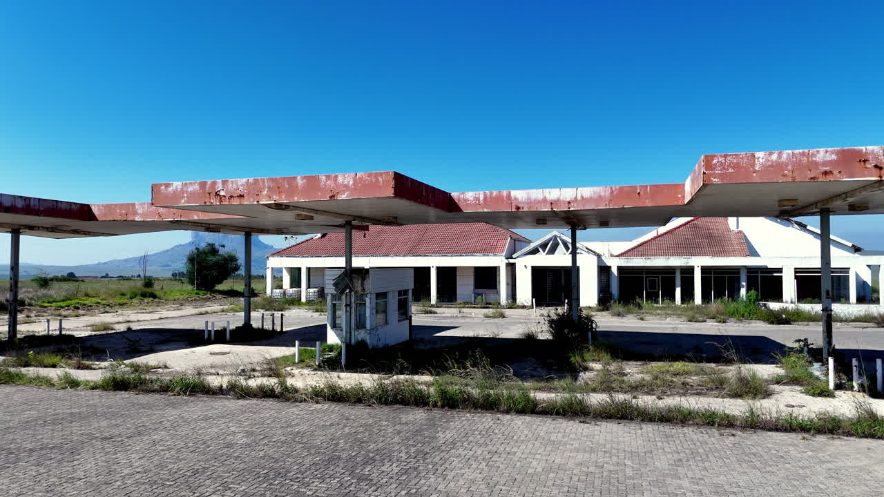 Vecchia stazione di servizio fatiscente e abbandonata in campagna, carrellata aerea