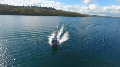 Toma-Aérea-De-Seguimiento-De-Un-Barco-Pesquero-Navegando-En-El-Lago-Taupo,-Nueva-Zelanda.