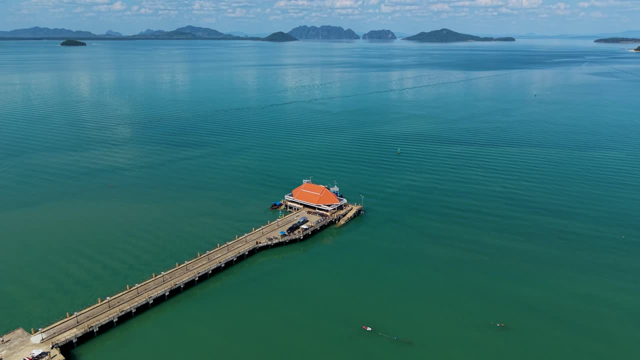 Veduta aerea del Molo di Koh Lanta Old Town che si estende nelle acque turchesi del Mare delle Andamane, con isole tropicali sullo sfondo sotto cieli azzurri e sereni, che mostra la serena bellezza costiera della Thailandia.