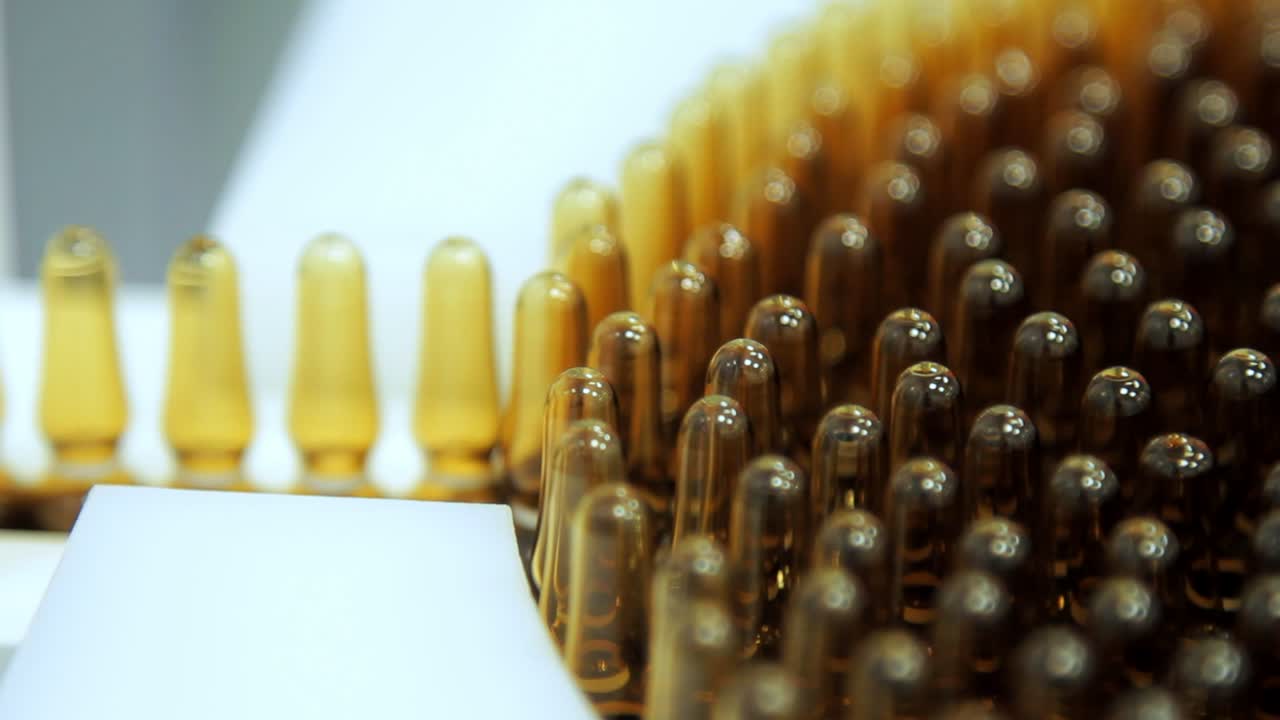 Manufacturing at pharmacy factory. Macro of medical vials on production line