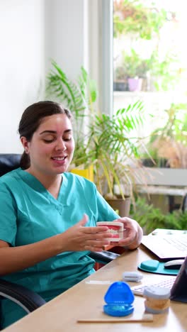 dentist showing how to use teeth whitening device with educational model of oral cavity.