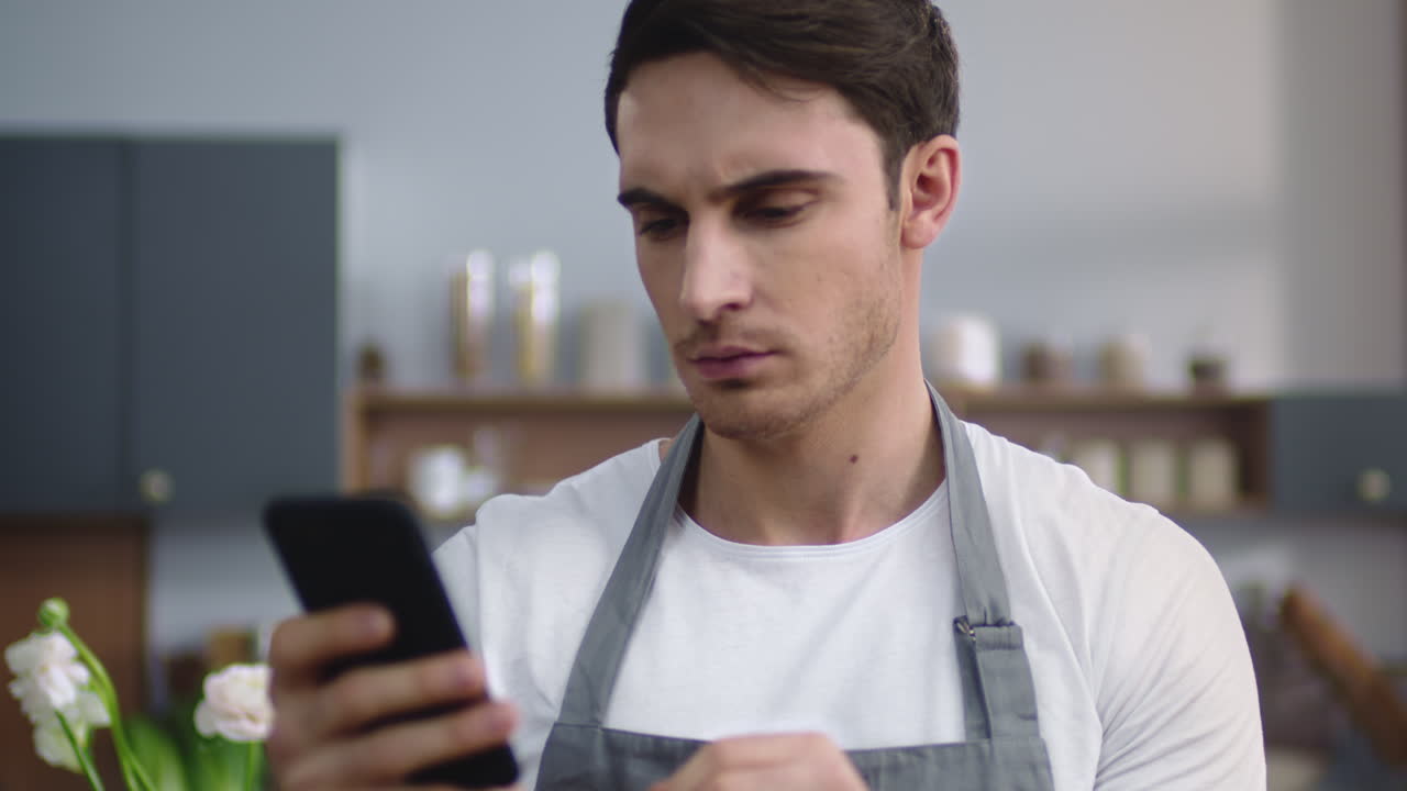 el chef está mirando la pantalla del teléfono en la cocina.