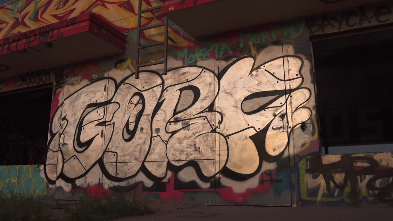 Street artist spray painting graffiti onto abandoned urban building