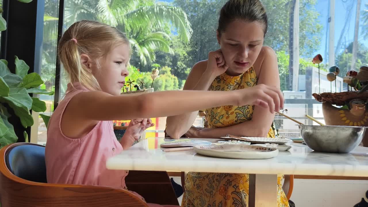 mãe e filha pintando cerâmica em um café