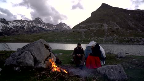 couple of travelers at dusk near a campfire