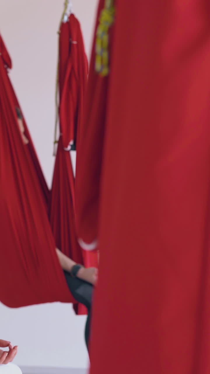meditating group sits in butterfly position in oriental fly yoga hammocks with fingers in mudra position close view