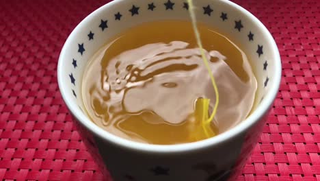 맛있는 건강한 아침 음료를 만들기 위해 뜨거운 물 머그잔에 천천히 담그는 강황 티백