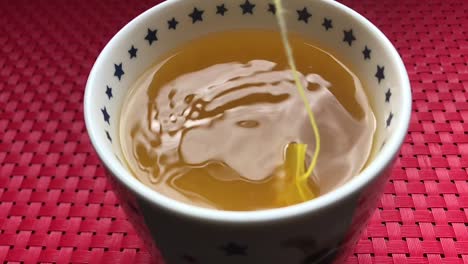 a turmeric tea bag being dunked slowly in a mug of hot water to make a delicious healthy morning beverage