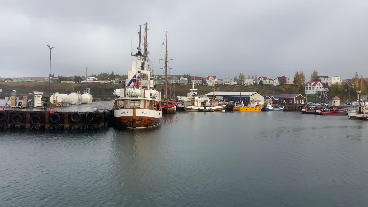 barcos típicos de madera islandeses amarrados en el puerto de husavik en un día lluvioso