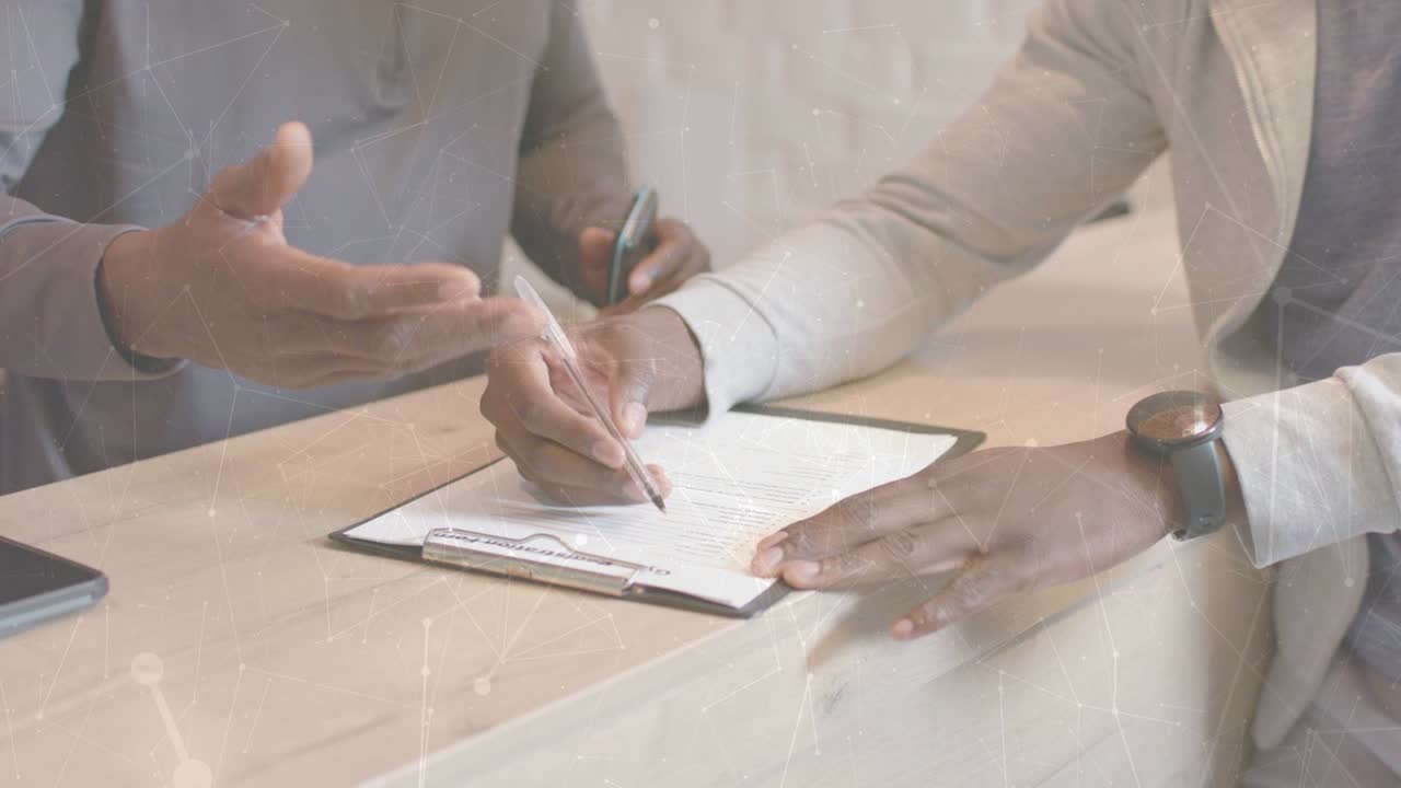 Staff guiding client at desk, pointing clipboard, handing pen while signing, completing paperwork