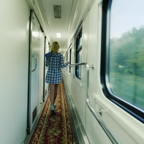 a woman with a towel is walking along the carriage of a passenger train 2