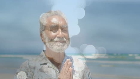 Animation-of-light-spots-over-senior-biracial-man-practicing-yoga-and-meditating