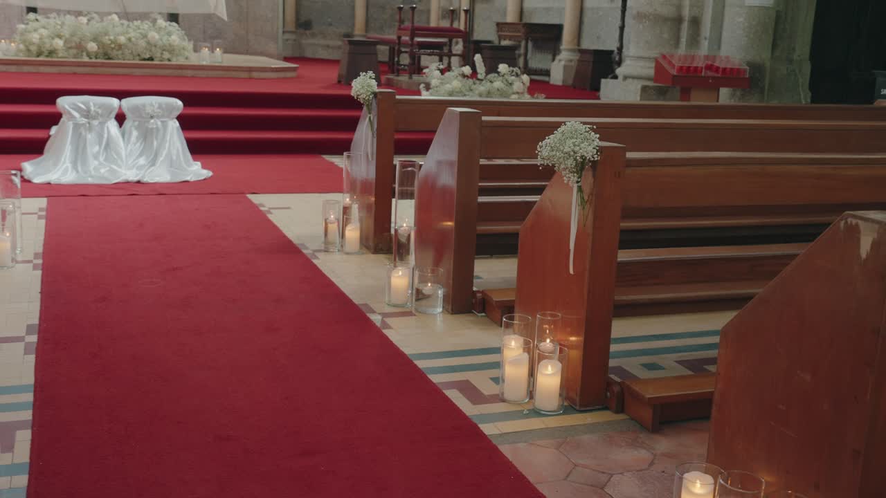 Romantic wedding aisle decorated with candles, flowers, and red carpet inside a traditional church