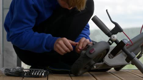 Close-up-shot-of-teenager-boy-furiously-changing-electric-scooter-tire-in-the-balcony