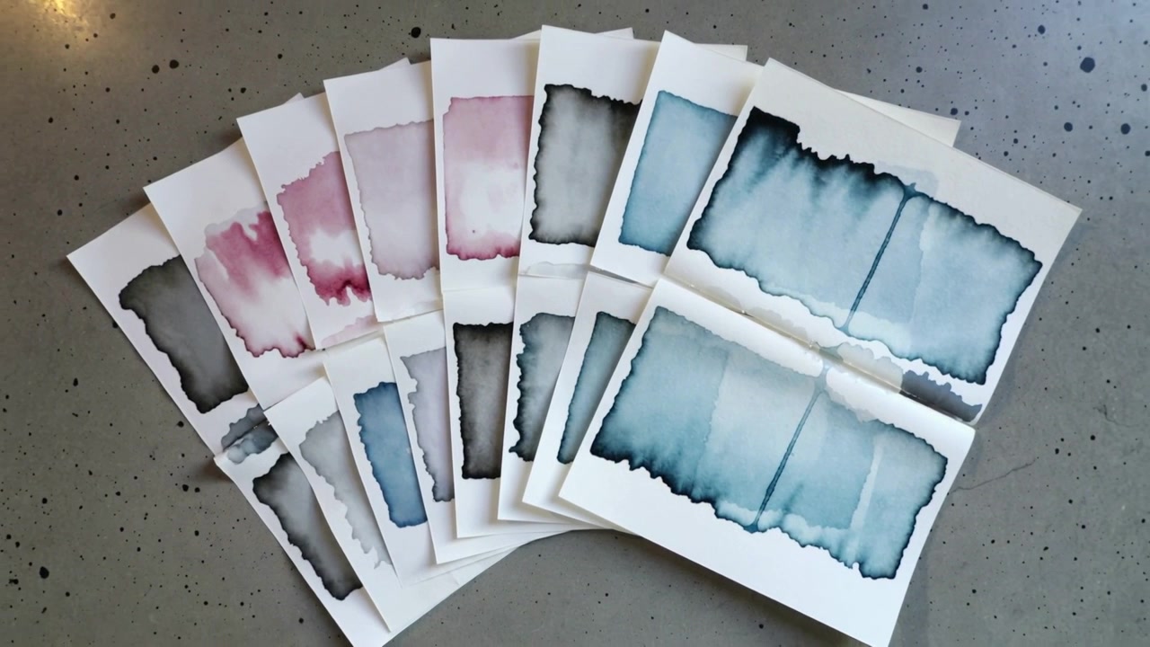 Pulling back cam showing fanned watercolor paper on speckled table, revealing color progression