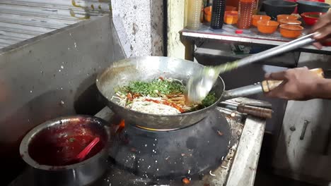 street food man is cooking pad noodle with egg at a night food market in india, quick-cooking chinese noodles close-up, cooking homemade quick pasta soup