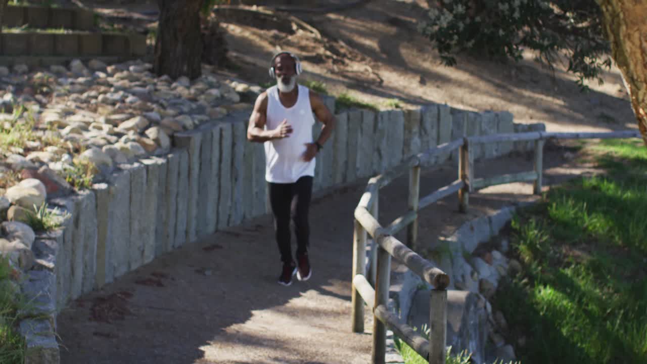 시니어 아프리카계 미국인 남자가 바 ⁇ 가의 도로에서 달리기를 연습하고 있습니다.