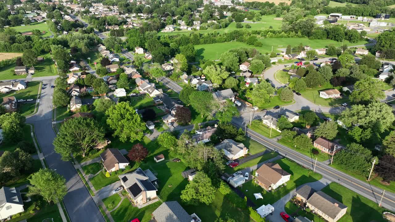 Lush green suburb neighborhood during sunny day in America. Aerial flyover shot. Quaint and quiet residential houses in summer season. Pennsylvania state, USA