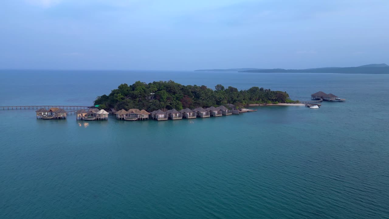 Song Saa Private Island, a luxury resort connecting two islands with a pier and overwater bungalows. Marvelous aerial view flight wide orbit overview drone