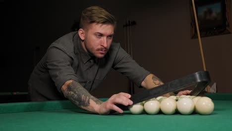 triangle of billiard balls. a man getting ready to start a game of billiards.