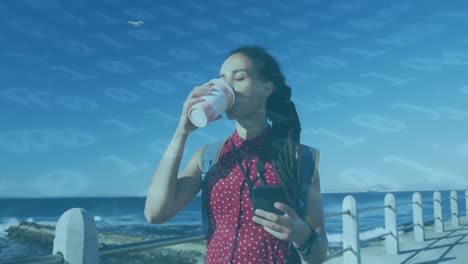 animation of floating numbers over woman drinking coffee and using smartphone on promenade