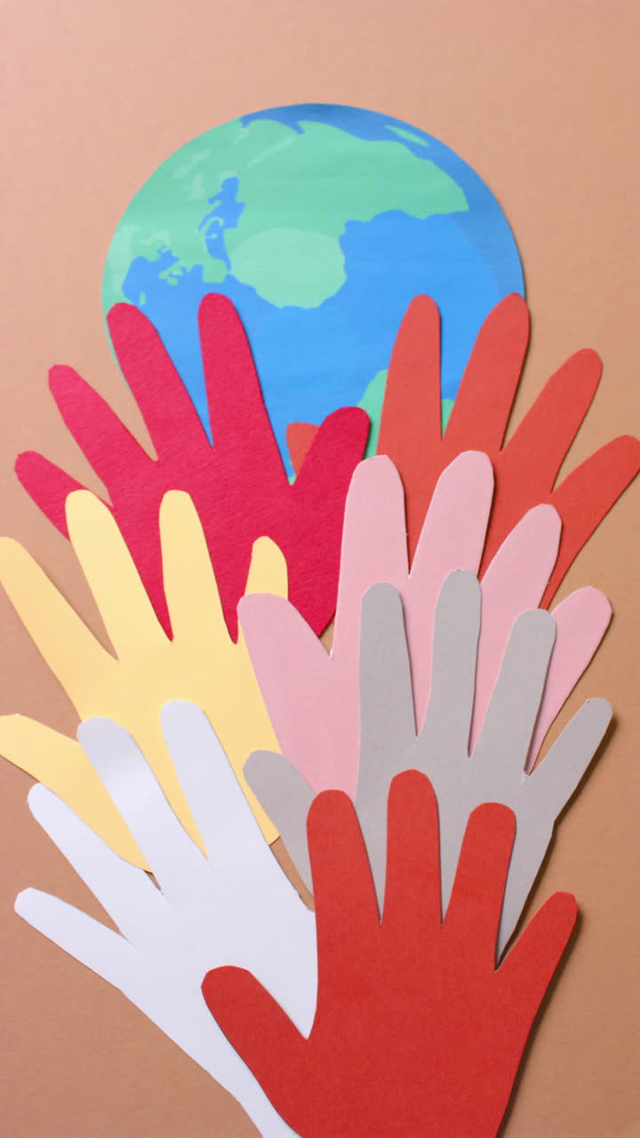 Vertical video of hands with globe made of colourful paper on green background with copy space