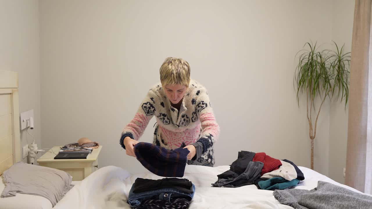 Woman folding clothes on bed