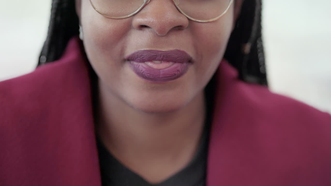 fotografía de cerca de jóvenes afroamericanas atractivas con labios rosados y trenzas en gafas de aviador con abrigo rosado