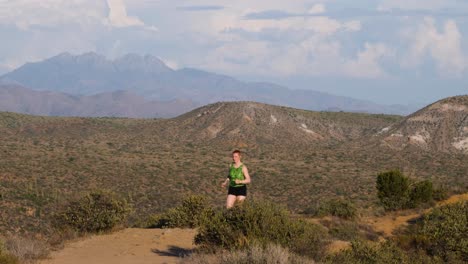 Corredor-En-Las-Montañas-De-Arizona-En-Un-Sendero-De-Tierra-Vistiendo-Un-Leotardo-Verde-Y-Pantalones-Cortos-Negros