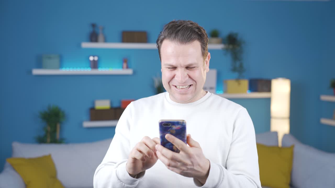 un hombre maduro en casa está enfocado y concentrado en su teléfono inteligente mirando noticias, mensajes, correos electrónicos que lo harán feliz.